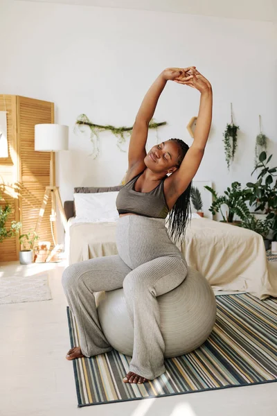 Afrikalı hamile bir kız sabahları yatak odasında spor salonunda egzersiz yapıyor.