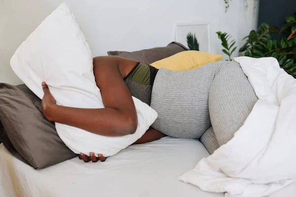 베개를 껴안고 분만중 침대에 고통을 아프리카 — 스톡 사진