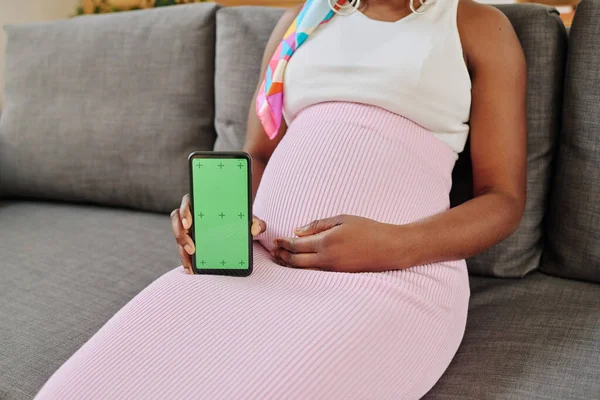 孕妇坐在沙发上的特写 展示她的手机屏幕 — 图库照片