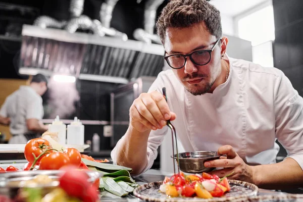 Joven Chef Anteojos Poniendo Ensalada Verduras Plato Mientras Trabaja Cocina — Foto de Stock