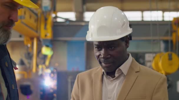 成熟的非洲裔美籍硬帽和正装工程师潘宁拍摄与工厂高级高加索技师商榷工作 — 图库视频影像