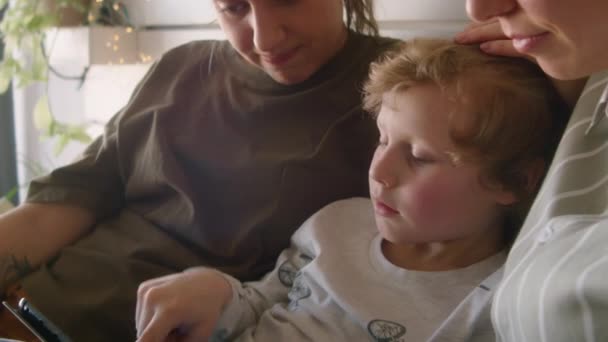 Niño Discutiendo Algo Tableta Digital Con Madres Lesbianas Mientras Descansan — Vídeo de stock