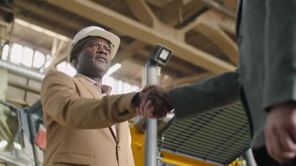 中老年非洲裔美国工程师头戴硬礼帽 穿着正装 与工厂同事握手的低角度镜头 — 图库视频影像