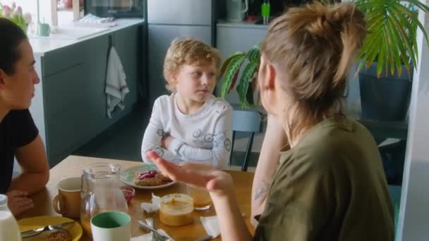 Roztomilý Malý Chlapec Sedí Kuchyňského Stolu Říká Něco Lesbickým Matkám — Stock video