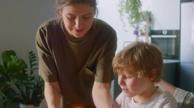 Mutlu LGBTQ ailesi evdeki çocuğun doğum gününü kutluyor. Küçük oğlu pastaya mum üflüyor. Sevgi dolu lezbiyen anneler onu selamlıyor ve öpüyor.