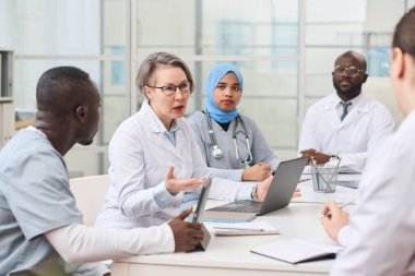 Bir grup doktor ofiste toplantı yapıyor ve zor bir hasta hastalığını tartışıyorlar.