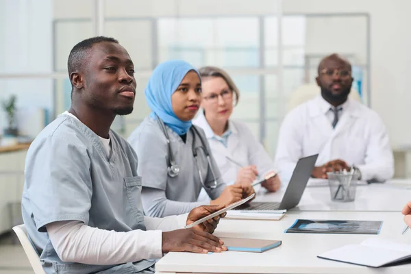 Group of doctors sitting at medical conference in office and making notes in gadgets