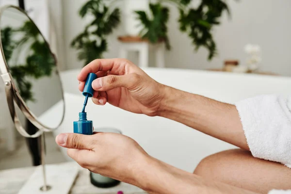 stock image Close-up of man opening varnish with blue color to color his nails after manicure