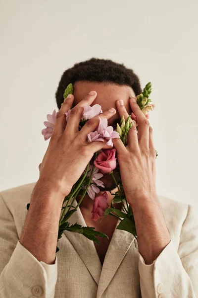 Beyaz Arka Planda Ellerini Çiçeklerle Kaplayan Genç Bir Adamın Portresi — Stok fotoğraf