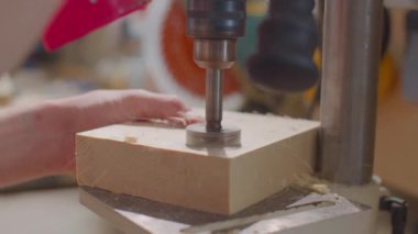 Marangozun ahşap delme atölyesinde delik testeresiyle odun keserken yakın çekim.