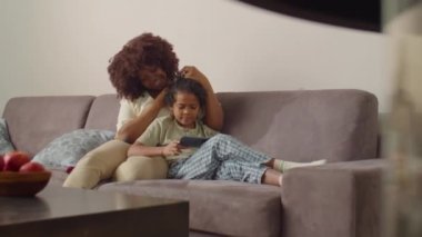 Afrikalı Amerikalı anneyi sevmek, küçük oğluyla koltukta oturmak, gülümsemek ve onunla evdeki oturma odasında dijital tablette bir şeyler tartışmak.