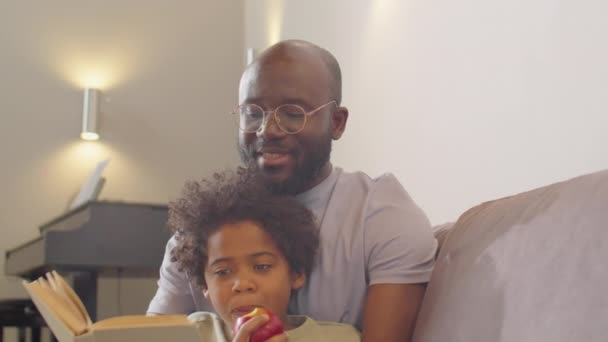 Pequeño Niño Afroamericano Comiendo Manzana Escuchando Padre Mientras Lee Libro — Vídeos de Stock
