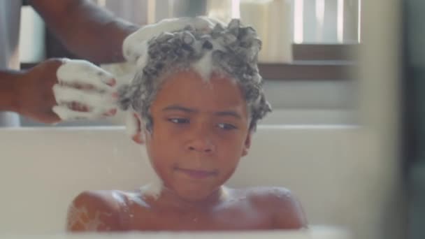 在父亲洗头的时候 非洲裔美国人坐在充满水的浴缸里 拍一张倾斜的照片 — 图库视频影像