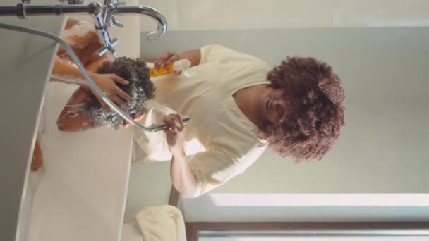 Pionowe Ujęcie Afroamerykańskiej Matki Nakładającej Szampon Włosy Małego Syna Podczas — Wideo stockowe