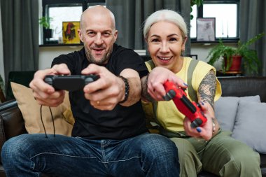 Modern olgun beyaz erkek ve kadın aşıklar evde oyun oynayarak vakit geçiriyorlar.