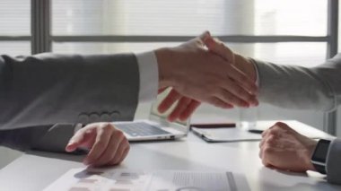 Formalite giymiş iki iş adamının el sıkışırken ve ofis masasında tartışırken yakın plan çekimleri.