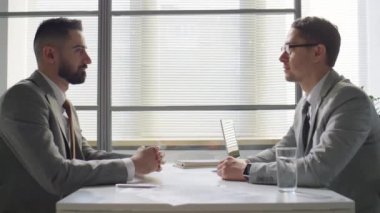 Orta doğulu ve Kafkasyalı iş adamlarının masada tokalaşırken ve el sıkışırken yan görünümü