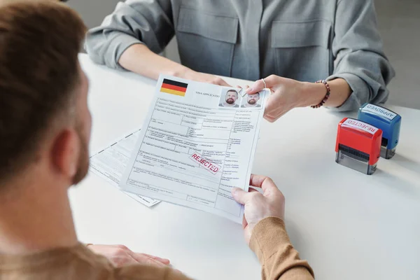 stock image High angle view of unrecognizable consular officer returning visa application form paper with rejected stamp on it to applicant