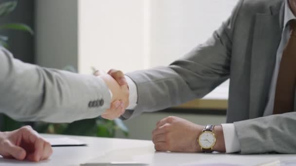 オフィスのテーブルで一緒に座っている間に正式なスーツ笑顔で中東のビジネスマンのショットを傾け 男性同僚と握手 — ストック動画