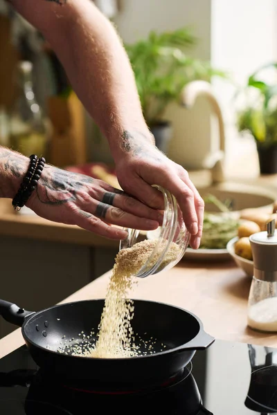 Nierozpoznawalny Mężczyzna Wytatuowanymi Rękami Gotujący Coś Kuchni Domu Wlewając Nasiona — Zdjęcie stockowe