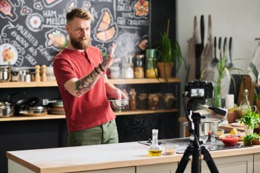 Kafkasyalı yemek blogcusu, hamur yapmak için masa yüzeyi hazırlarken, havadaki vlog tozlama ununun içeriğini oluşturuyor