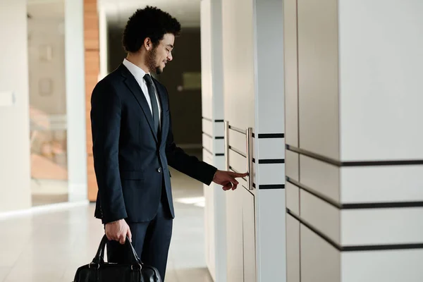 オフィスビルの廊下にエレベータースタンドを使用してブリーフケースに合う若いビジネスマン — ストック写真