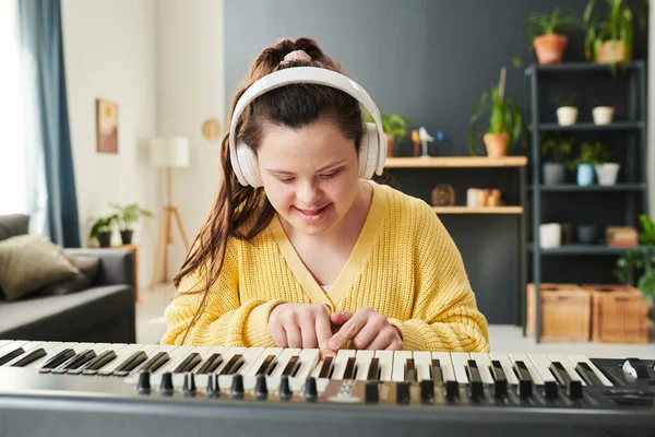 带着耳机在家里学习弹奏电子琴的快乐的白人女孩的画像 — 图库照片