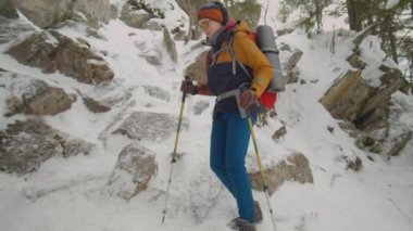 Dişi turist, kış günü dağlarda yürüyüş yaparken dik kayalıklarda yürüyor.