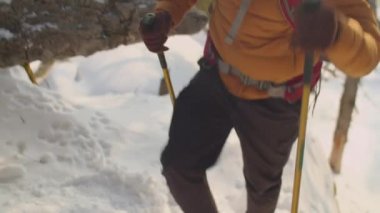 Sırt çantalı uzun saçlı turist ve yürüyüş direkleri dağlarda dik patikalara tırmanıyor ve güneşli kış günlerinde gezerken durup etrafa bakınıyor.