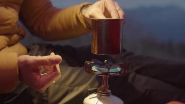 Kış kampında çadırda otururken, portatif gaz sobasının üzerine çelik bardak koyan adamı yukarı kaldır.