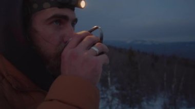 Sakallı turistin akşamları kamp alanında durup çay içerken ve kış tatilini doğada geçirirken dikkatlice uzaktan bakarken çekilen görüntülerini.