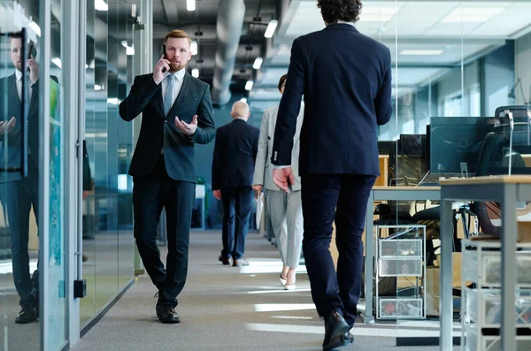 Jovem Empresário Terno Falando Celular Enquanto Caminha Longo Corredor Escritório — Fotografia de Stock