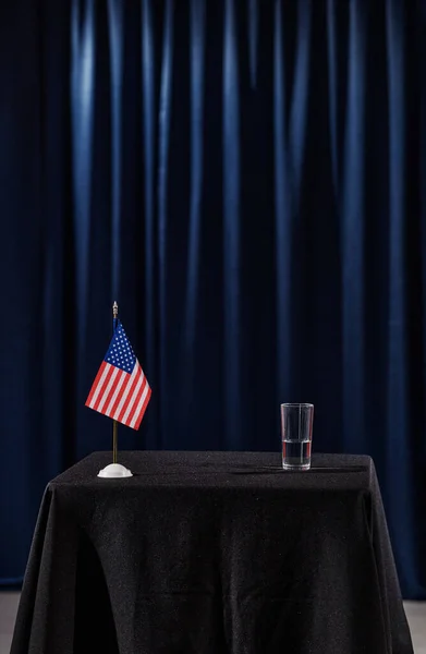 会議でスピーカーのための水とアメリカの旗のガラスとのトリビューンの垂直画像 — ストック写真