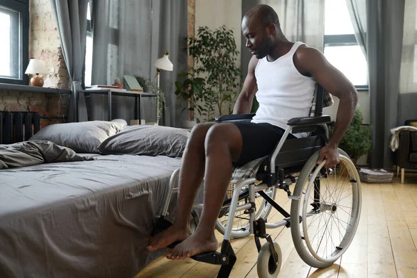 Afrykanin Niepełnosprawnością Podjeżdża Łóżka Wózku Inwalidzkim Kładzie Się Łóżku Odpoczywa — Zdjęcie stockowe