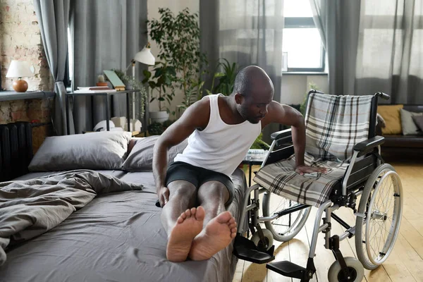 Afrykanin Próbuje Usiąść Wózku Inwalidzkim Relaksie Łóżku Podczas Rehabilitacji Domu — Zdjęcie stockowe