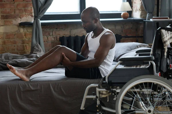 Afrykański Młody Facet Niepełnosprawnością Stojący Łóżka Bez Pomocy Próbujący Usiąść — Zdjęcie stockowe