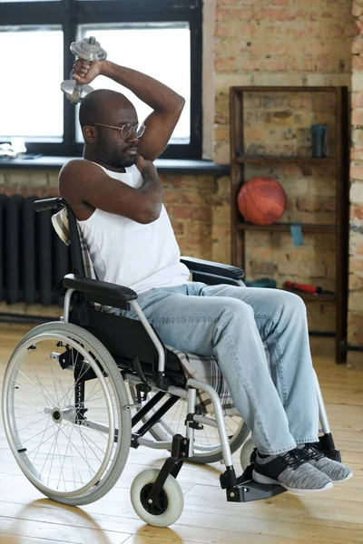 自宅でリハビリテーション中に車椅子に座るダンベルを持つアフリカ系アメリカ人の男性 — ストック写真