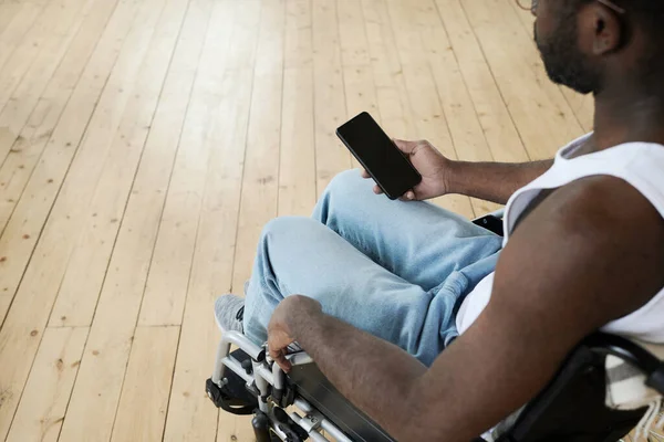 車椅子に座って携帯電話でメッセージを読んでいるアフリカの男性のクローズアップ — ストック写真