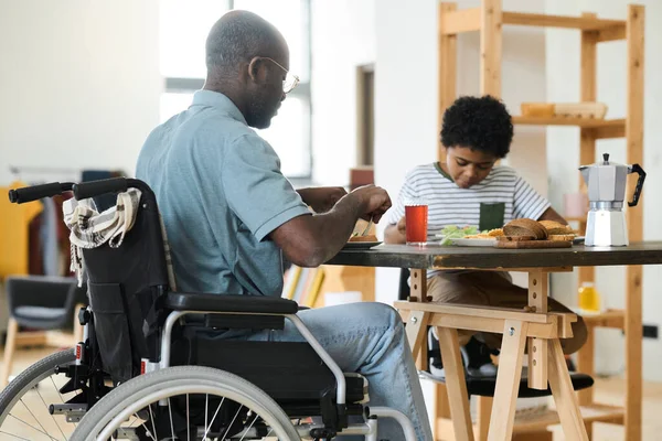 Вид Сзади Отца Инвалида Сидящего Столом Инвалидной Коляске Завтракающего Вместе — стоковое фото
