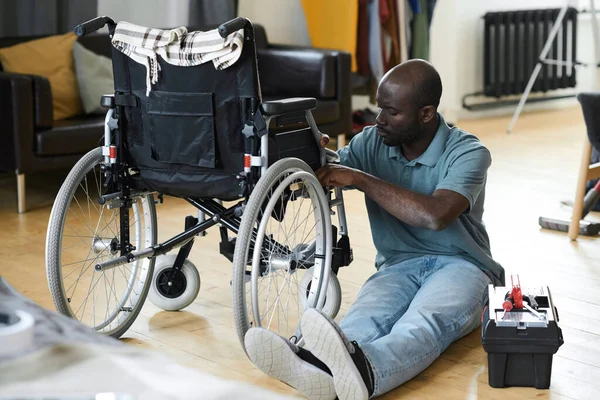 Африканский Инвалид Сидит Полу Чинит Сломанное Инвалидное Кресло Инструментами — стоковое фото
