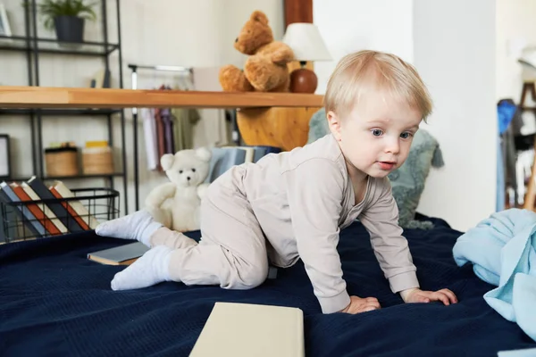 Malý Blonďatý Chlapec Pyžamu Učí Plazit Posteli Mezi Svými Hračkami — Stock fotografie