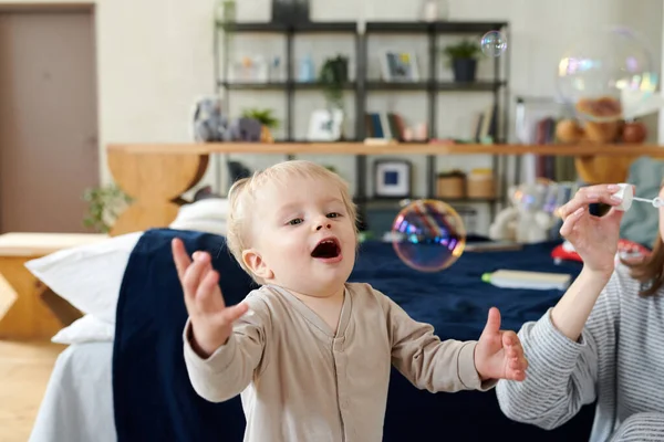 Roztomilé Malé Dítě Chytání Mýdlové Bubliny Foukání Jeho Mamkou Pokoji — Stock fotografie