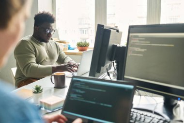 Ofis masasında laptoplarla çalışan programcılar yeni yazılımlar için kod yazıyorlar