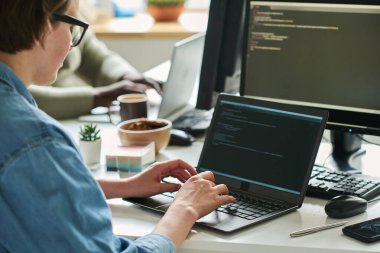 İnternet sitesine girebilmek için masadaki dizüstü bilgisayara kod yazan kadın programcı