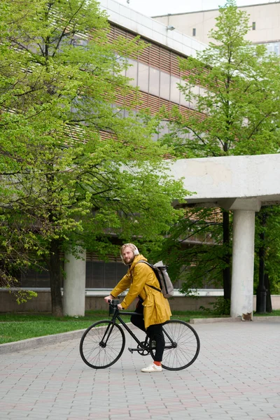 市内の交通手段として自転車を使用したリュックを持つ若い男の肖像 — ストック写真