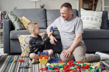 Genç baba evde boş zamanlarında küçük oğluyla oyuncak oynuyor.
