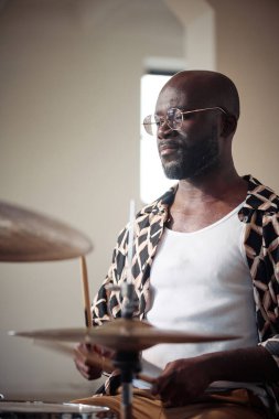 Bateri çalmak için bateri kullanan gözlüklü Afrikalı genç baterist.