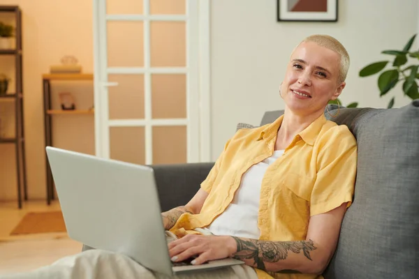 stock image Portrait of mature elegant woman with short hair smiling at camera while buying purchase online on laptop sitting on sofa