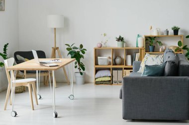 Modern oturma odasının yatay görüntüsü rahat kanepesi ve online çalışma için dizüstü bilgisayarı olan bir masa.