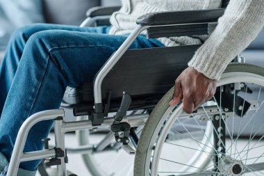 Özürlü Afrikalı adamın rehabilitasyonu sırasında hareket etmek için tekerlekli sandalye kullanması.